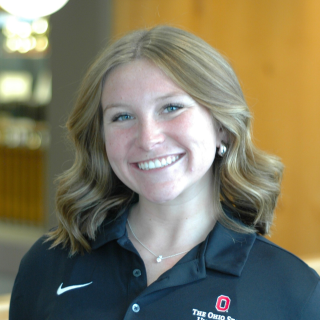 A woman in a black polo smiles