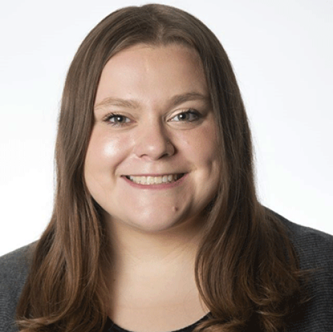 a white woman with brown hair and black blazer smiling