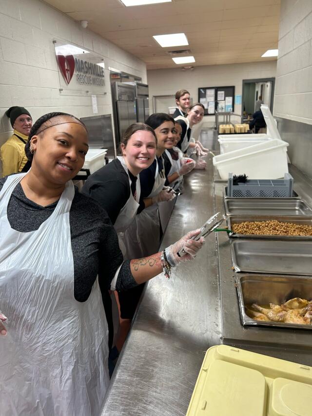 A group of 6 Buck-I-SERV participants works to prepare and serve meals