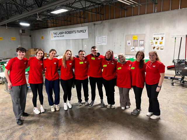 10 college student volunteers wearing red t-shirts in food pantry warehouse in Nashville