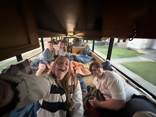 College students posing for selfie inside the Merry Green Marvel sleeper coach bus