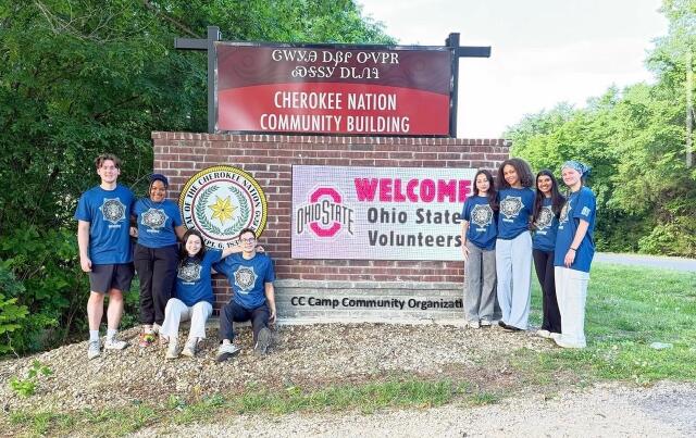 Students pose in front of a sign marking the entrance to Cherokee Nation.