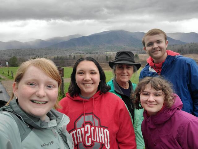 4 college student volunteers with Once Upon A Time staff member in front of mountain range