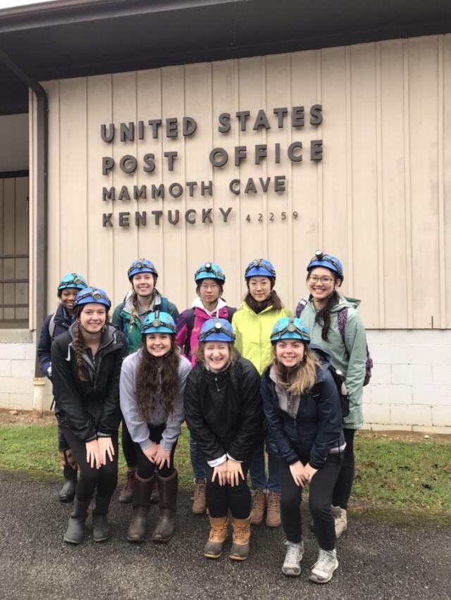 College students in hiking gear posing outside in front of the Post Office in Mammoth Cave, Kentucky
