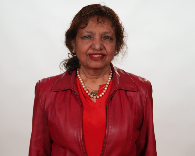 A smiling woman in a red shirt, red jacket and a pearl necklace