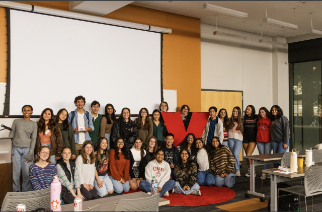 A group of students poses with a large X statue