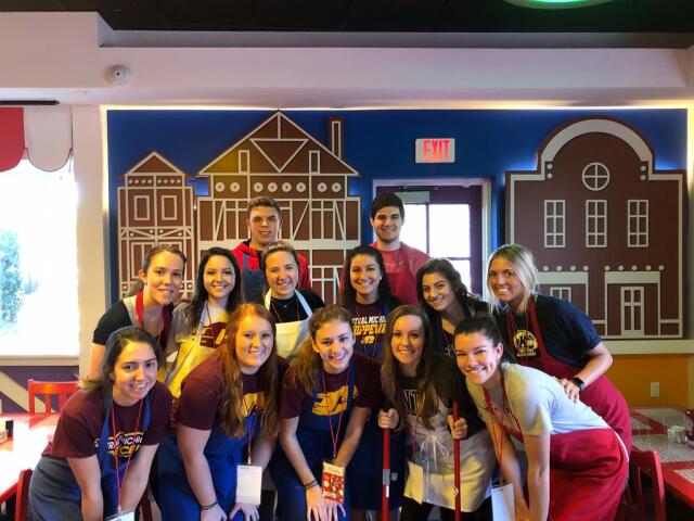Student volunteers wearing aprons posing together during Buck-I-SERV trip with Give Kids the World