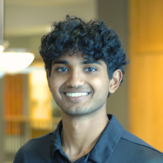 A man in a black polo smiles